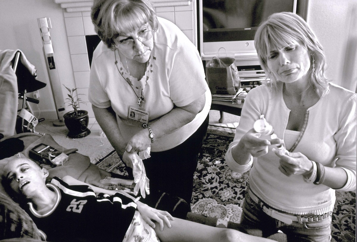 Cyndie French fights her emotions May 10, as she prepares to flush out Derek's catheter with saline solution before hospice nurse Sue Kirkpatrick, left, administers a sedative that will give the 11-year-old a peaceful death. "I know in my heart I've done everything I can," Cyndie says.