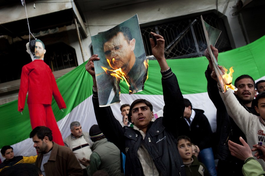 People burn portraits of Syrian President Bashar Assad during a demonstration against his regime in the outskirts of Idlib, northern Syria, Feb. 26, 2012. (Rodrigo Abd, Associated Press - February 26, 2012)