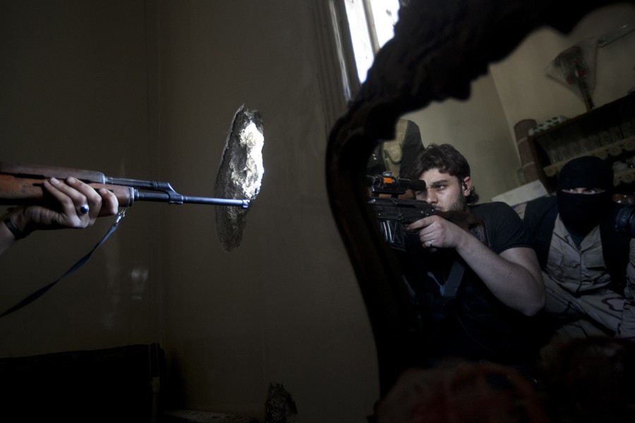 A rebel sniper aims at a Syrian army position, as he and another rebel fighter are reflected in a mirror inside a residential building in the Jedida district of Aleppo, Syria, Oct. 29, 2012. (Narciso Contreras, Associated Press - October 29, 2012)