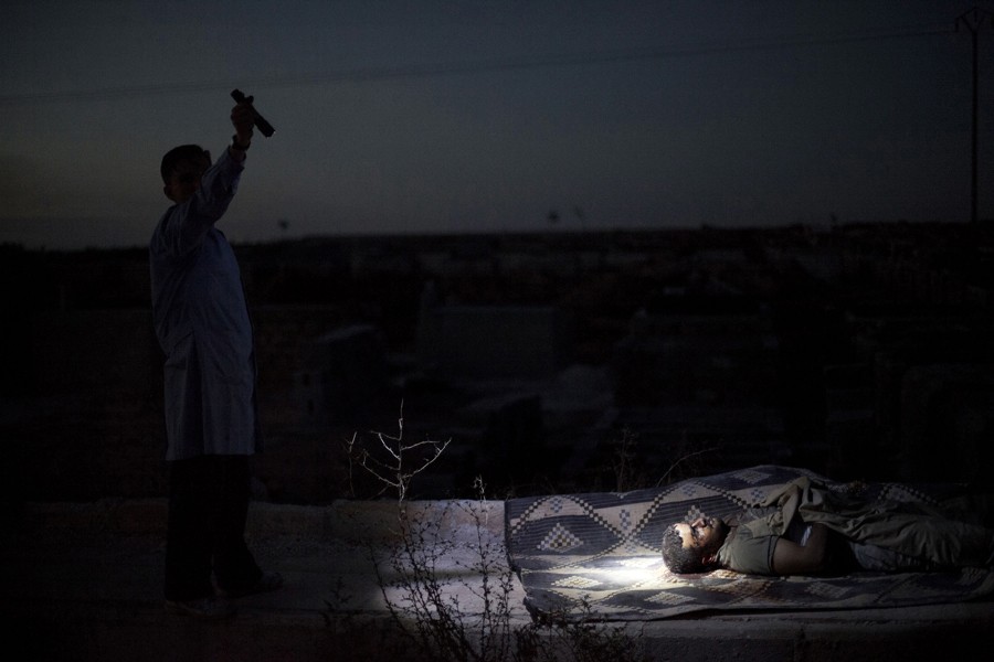 A man points a flashlight towards the body of a Syrian man killed by Syrian army shelling at a graveyard, in Aleppo, Syria, Oct. 13, 2012.   (Manu Brabo, Associated Press - October 13, 2012)