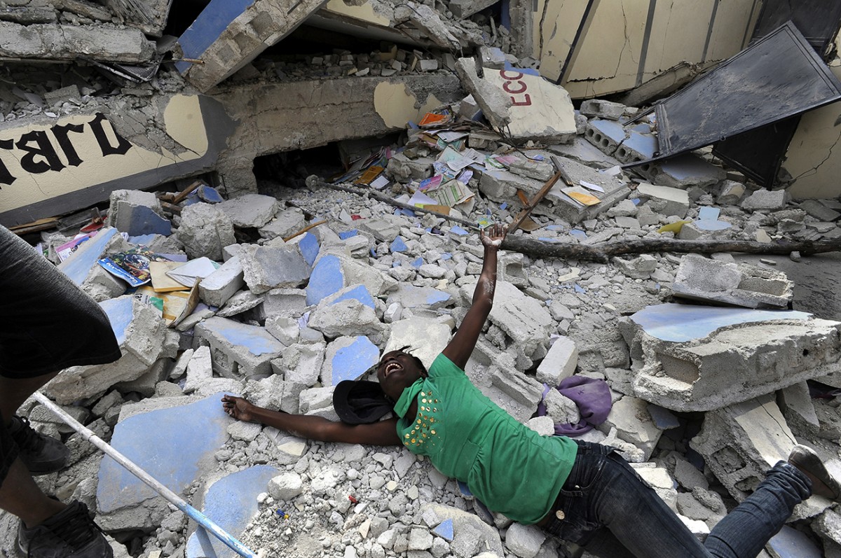 'Shattered Lives' Caked in the dust of crushed plaster and cement, Haitians dug out family members by hand and piled bodies on street corners as clusters of bloodied and dazed survivors pleaded for help. Cindy Tersme throws herself amid the rubble of Ecole St. Gerard, screaming in anguish as she searches for her brother Jean Gaelle Dersmorne, 14. 'I can see my brother’s feet but can't pull him out,' she said, weeping. (Carol Guzy, The Washington Post - January 15, 2010)