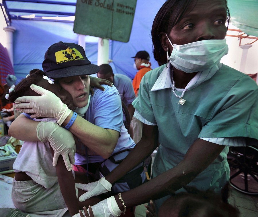 'Comfort'  The medical relief teams racing to help victims of the earthquake in Haiti were up against a grim biological fact: People trapped and injured are most likely to survive if rescued within 48 hours, and very few people are found alive more than six days after a disaster. Proyecto America, a Christian disaster relief team with international volunteers, provides food and medical assistance at a camp in Cite Soleil. Nurse Marilibia Concepcion consoles Setline Premero, 8. (Carol Guzy, The Washington Po
