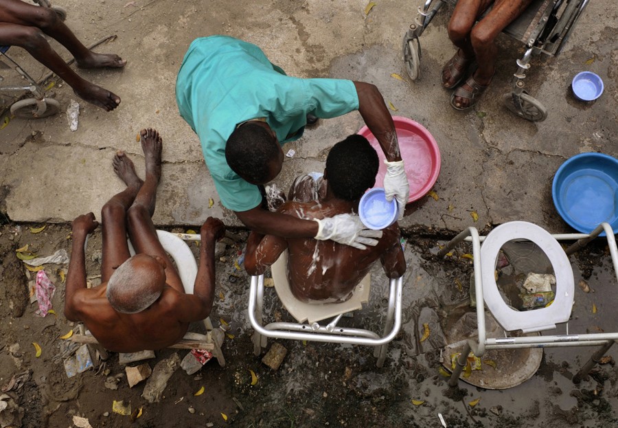 'Daily Duties' Phoncly Raphael bathes a group of men at the Azil Communal Home. Sanitation at the home remains a problem for residents living in the community. In Haitian Creole, the old are called 'gran moun,' and they are relatively few. Those 65 and older make up just 3.4 percent of Haiti's population, compared with 13 percent in a developed country such as the United States, because to attain such seniority in a nation beset by high infant mortality, poverty and disease is an accomplishment. (Nikki Kahn
